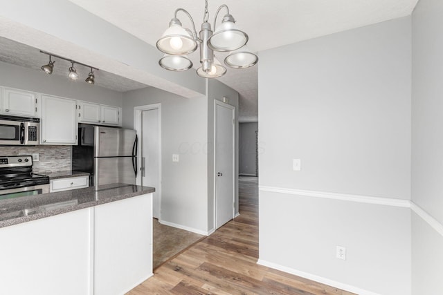 kitchen featuring tasteful backsplash, appliances with stainless steel finishes, light wood-style floors, white cabinets, and baseboards