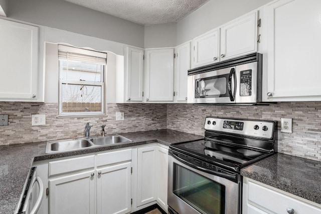 kitchen with stainless steel appliances, dark countertops, white cabinetry, a sink, and a textured ceiling