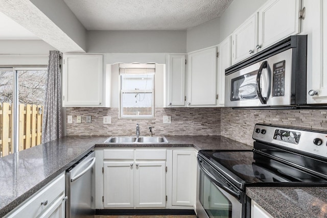 kitchen with stainless steel appliances, tasteful backsplash, a sink, and white cabinets