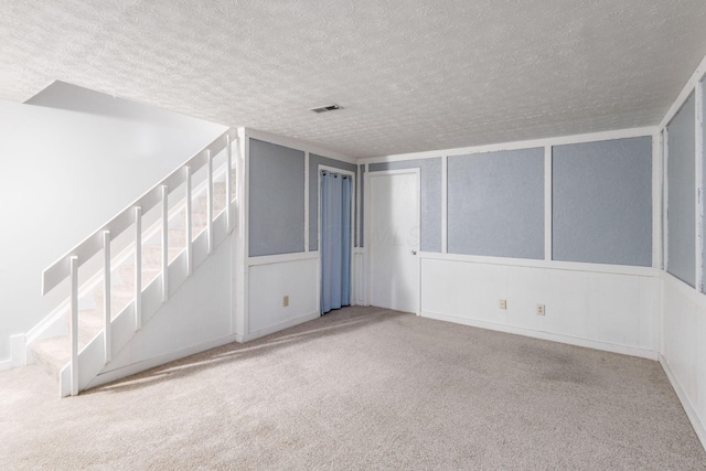 empty room featuring a textured ceiling, carpet flooring, and visible vents