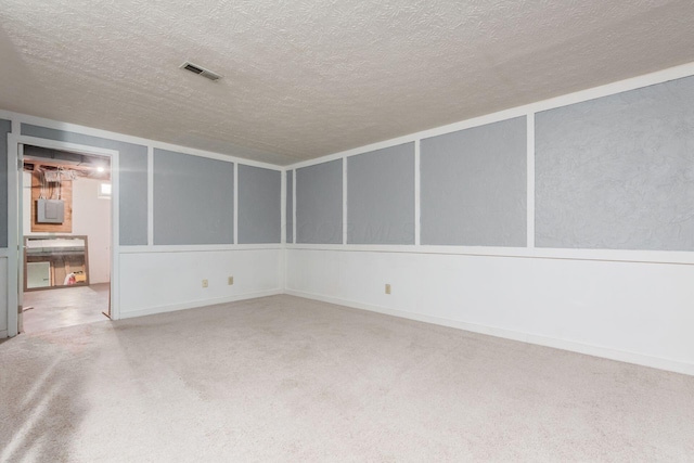 carpeted spare room featuring visible vents, electric panel, and a textured ceiling