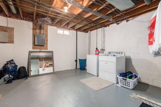 below grade area featuring washer and clothes dryer, electric panel, and concrete block wall