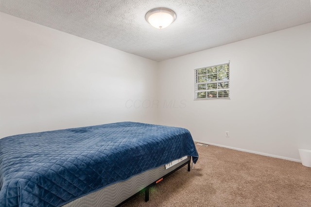 carpeted bedroom with a textured ceiling and baseboards