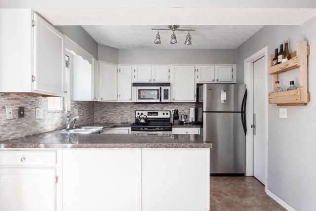 kitchen featuring tasteful backsplash, appliances with stainless steel finishes, white cabinets, a sink, and a peninsula