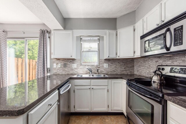 kitchen with a peninsula, white cabinetry, appliances with stainless steel finishes, and a sink