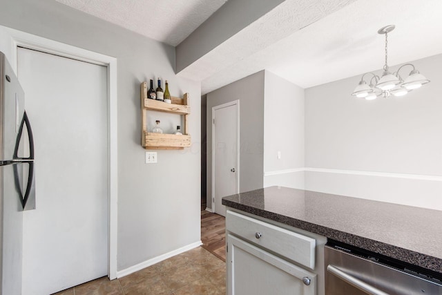 kitchen featuring baseboards, dark countertops, an inviting chandelier, stainless steel appliances, and pendant lighting