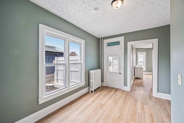 interior space with light wood finished floors, radiator heating unit, baseboards, and a textured ceiling