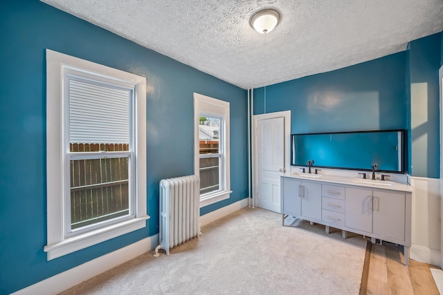 interior space with radiator, light colored carpet, a textured ceiling, and baseboards