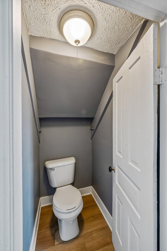 bathroom featuring baseboards, toilet, and wood finished floors