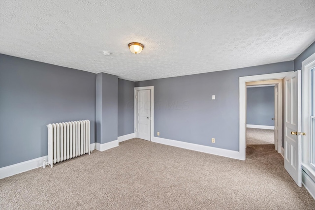 unfurnished room with a textured ceiling, carpet floors, radiator heating unit, and baseboards