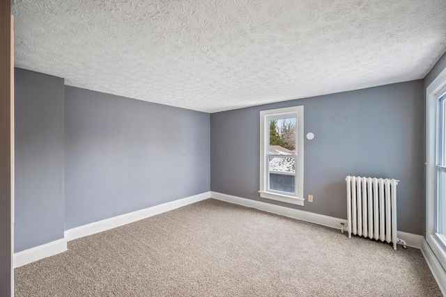 carpeted spare room featuring radiator, a textured ceiling, and baseboards