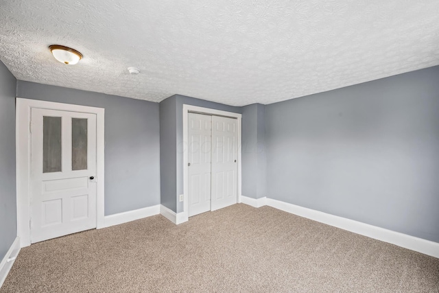 unfurnished bedroom with a textured ceiling, a closet, baseboards, and carpet flooring