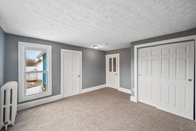 unfurnished bedroom featuring baseboards, carpet floors, a textured ceiling, and radiator