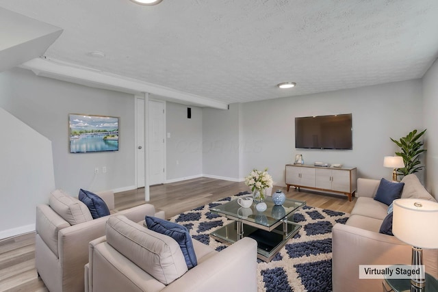 living area featuring a textured ceiling, baseboards, and wood finished floors