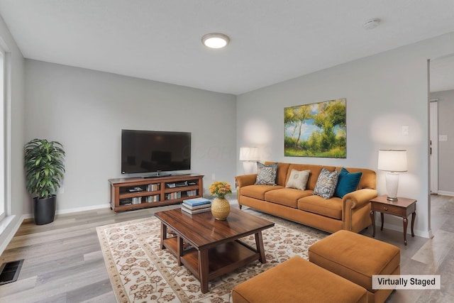 living room featuring baseboards, visible vents, and light wood finished floors