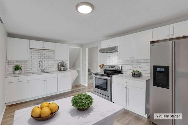 kitchen with stainless steel appliances, white cabinetry, a sink, and under cabinet range hood