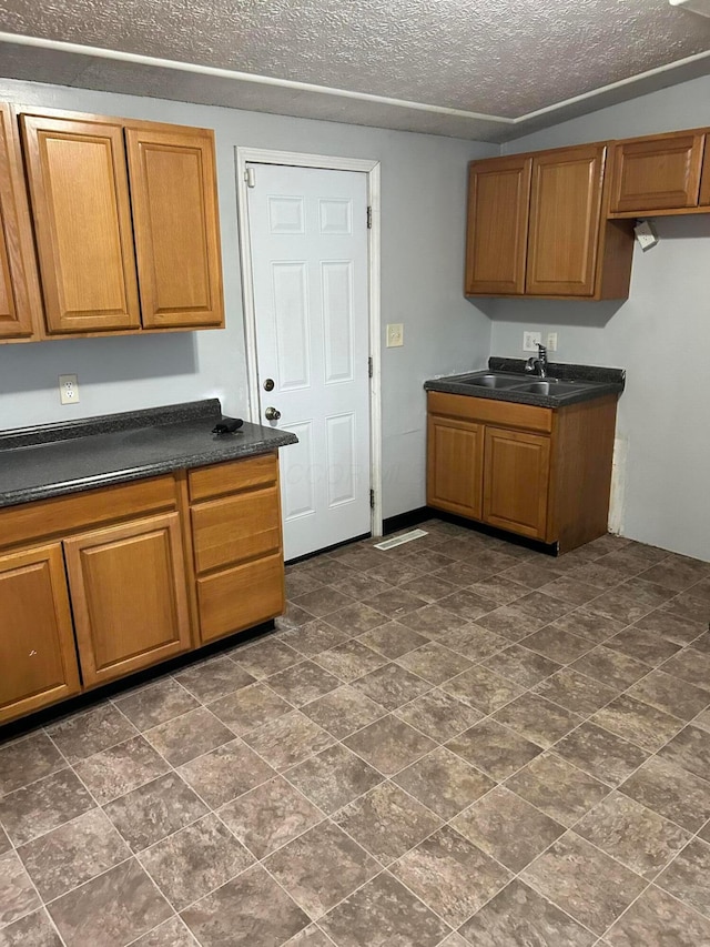 kitchen featuring dark countertops, a sink, and brown cabinets