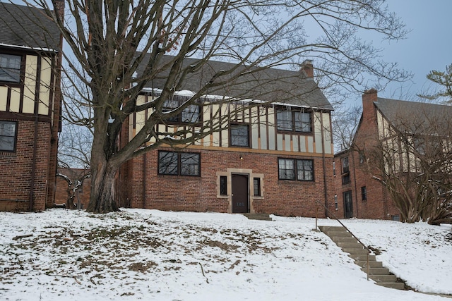 snow covered back of property with brick siding and stucco siding