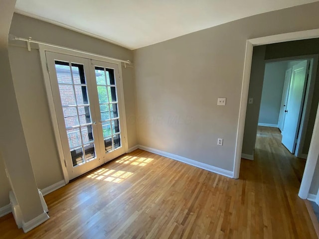 spare room featuring wood finished floors, french doors, and baseboards