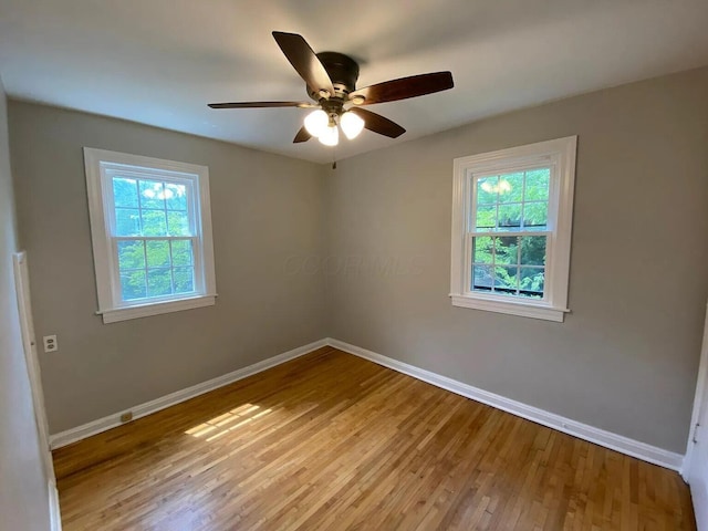 empty room with baseboards, a ceiling fan, and light wood finished floors