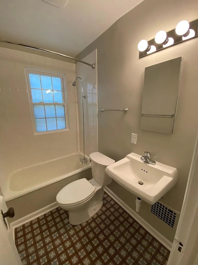 bathroom featuring toilet, shower / bathing tub combination, and a sink