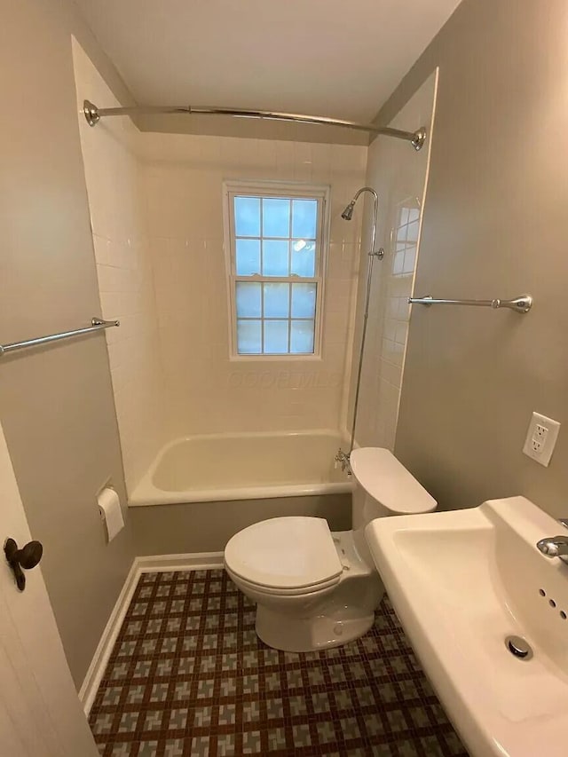 bathroom with washtub / shower combination, toilet, baseboards, and a sink