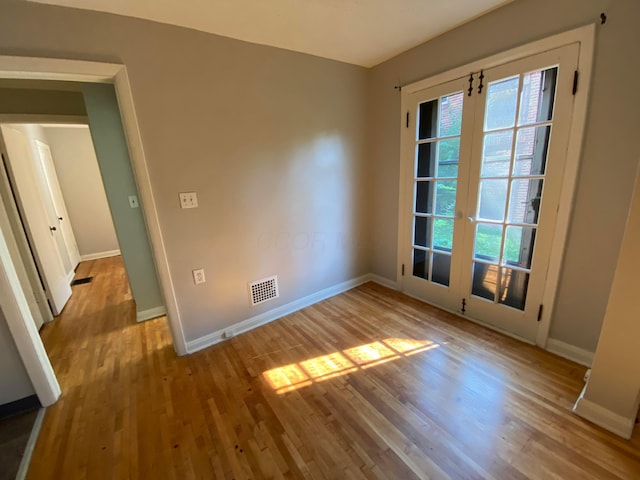 spare room with wood finished floors, visible vents, french doors, and baseboards