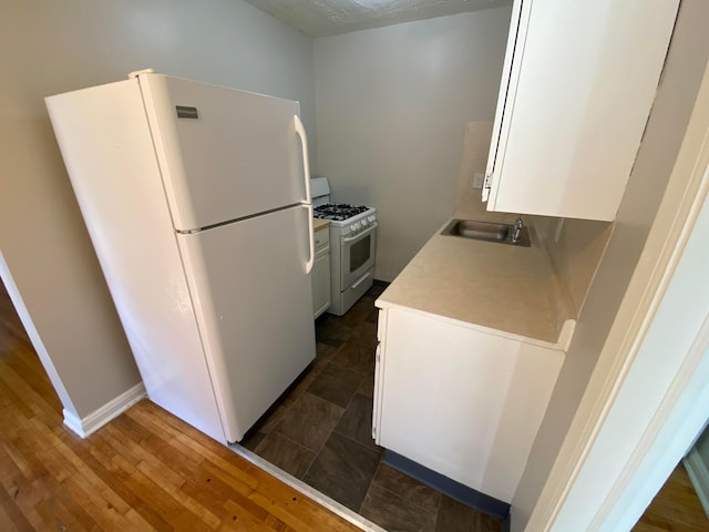 kitchen featuring a sink, dark wood-style floors, white cabinetry, white appliances, and light countertops