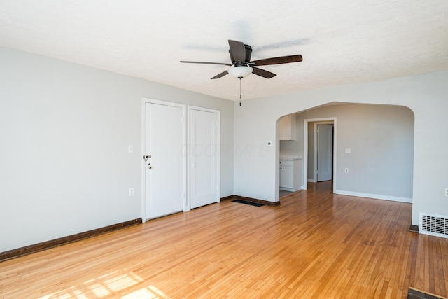 spare room with visible vents, arched walkways, baseboards, and light wood-style flooring