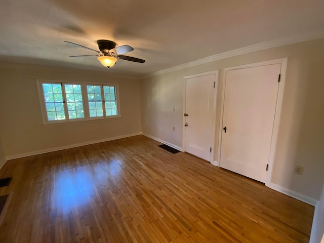 unfurnished bedroom with ceiling fan, wood finished floors, visible vents, baseboards, and crown molding