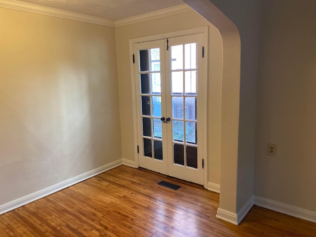 empty room with arched walkways, wood finished floors, visible vents, and crown molding