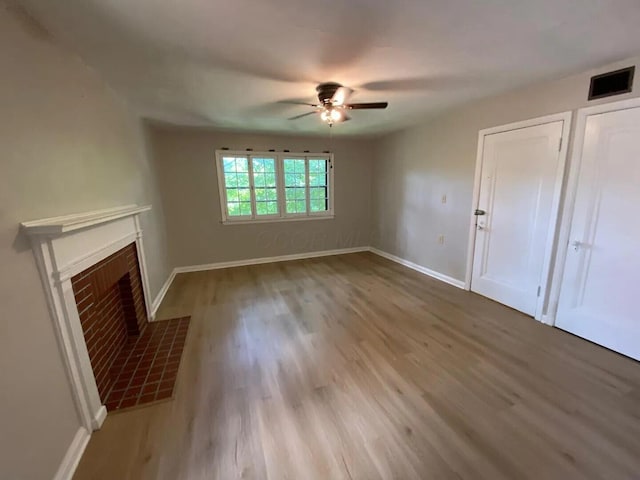 unfurnished living room with a fireplace with flush hearth, visible vents, and wood finished floors