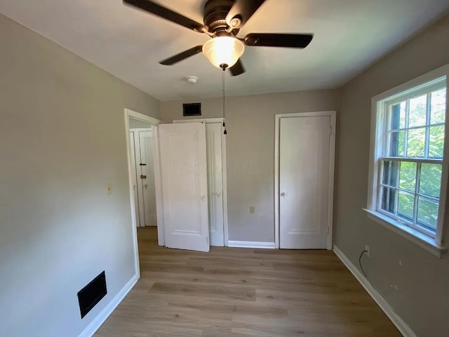 unfurnished bedroom with a ceiling fan, visible vents, light wood finished floors, and baseboards