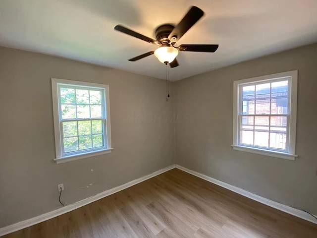 empty room with a ceiling fan, baseboards, and wood finished floors