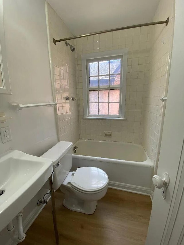 bathroom with toilet, a sink, tub / shower combination, and wood finished floors