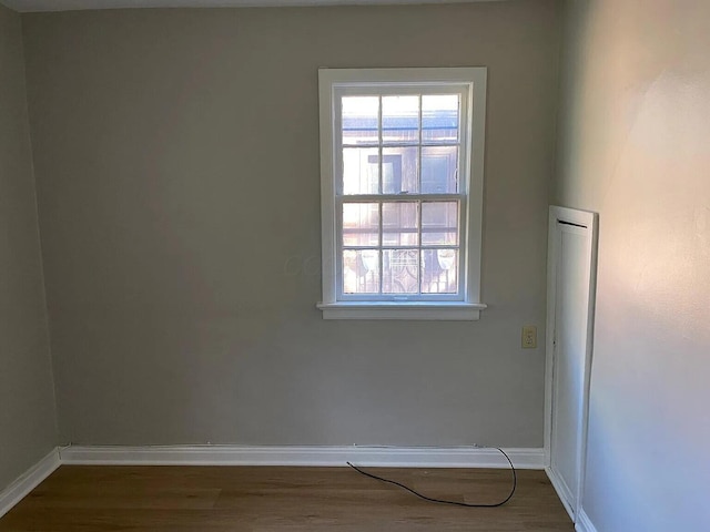 spare room with baseboards and wood finished floors