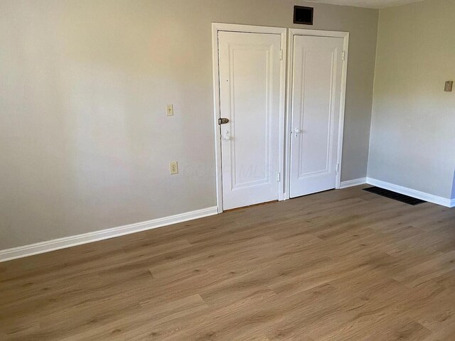 unfurnished bedroom featuring visible vents, baseboards, and wood finished floors