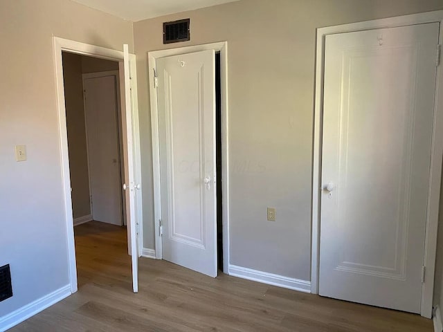 unfurnished bedroom with baseboards, visible vents, and wood finished floors