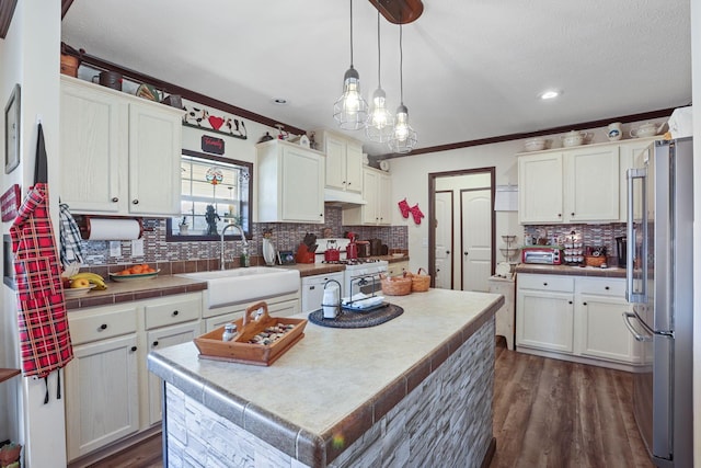 kitchen with white range with gas cooktop, white cabinetry, a sink, and freestanding refrigerator