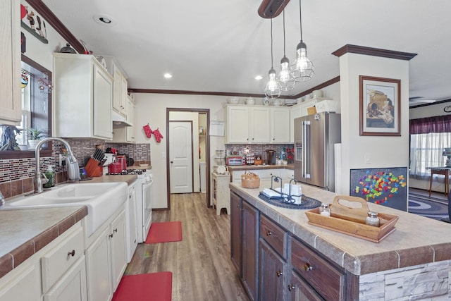 kitchen featuring a kitchen island, high end fridge, white gas range, white cabinetry, and a sink