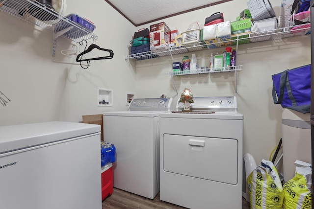 laundry room featuring washing machine and dryer, laundry area, a textured ceiling, and wood finished floors