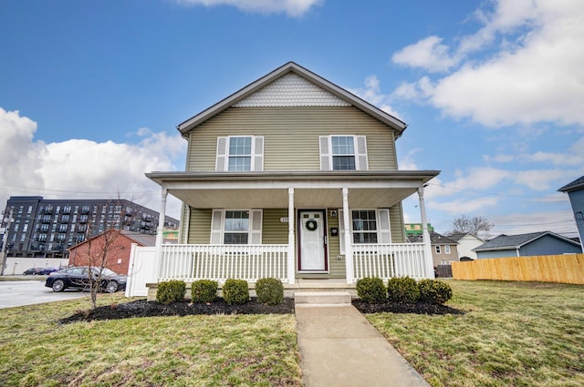 view of front facade with a porch, a front yard, and fence