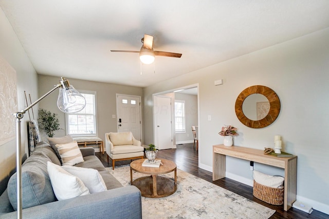 living area featuring dark wood-style floors, a ceiling fan, and baseboards