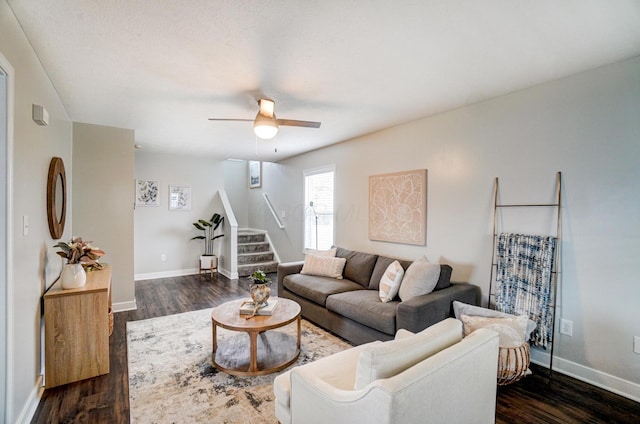 living area featuring stairway, baseboards, dark wood-type flooring, and a ceiling fan