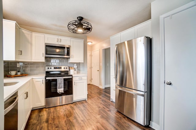 kitchen with backsplash, wood finished floors, white cabinetry, stainless steel appliances, and light countertops