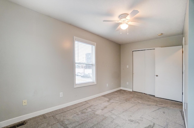 unfurnished bedroom featuring visible vents, baseboards, carpet floors, a closet, and a ceiling fan