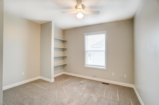 carpeted empty room with visible vents, baseboards, and a ceiling fan