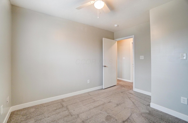 carpeted spare room featuring ceiling fan and baseboards