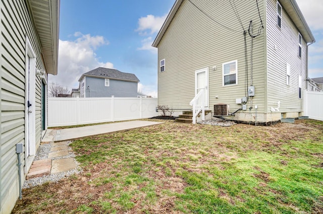 back of house featuring central air condition unit, entry steps, fence, a yard, and a patio area