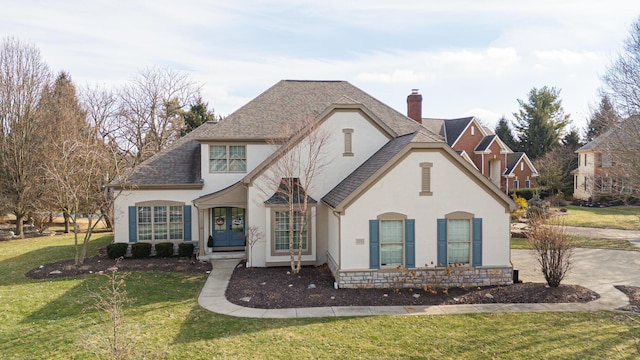 french provincial home featuring french doors, a chimney, stucco siding, a front yard, and stone siding